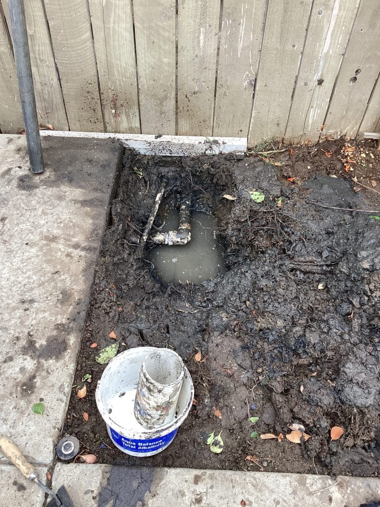 PVC fitting exposed in the hole after the tree roots were cut out