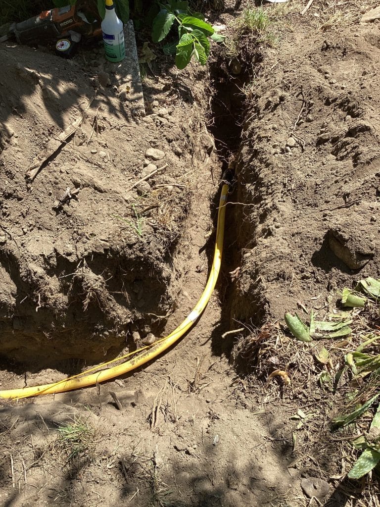 Yellow gas line laid in the open trench before backfill