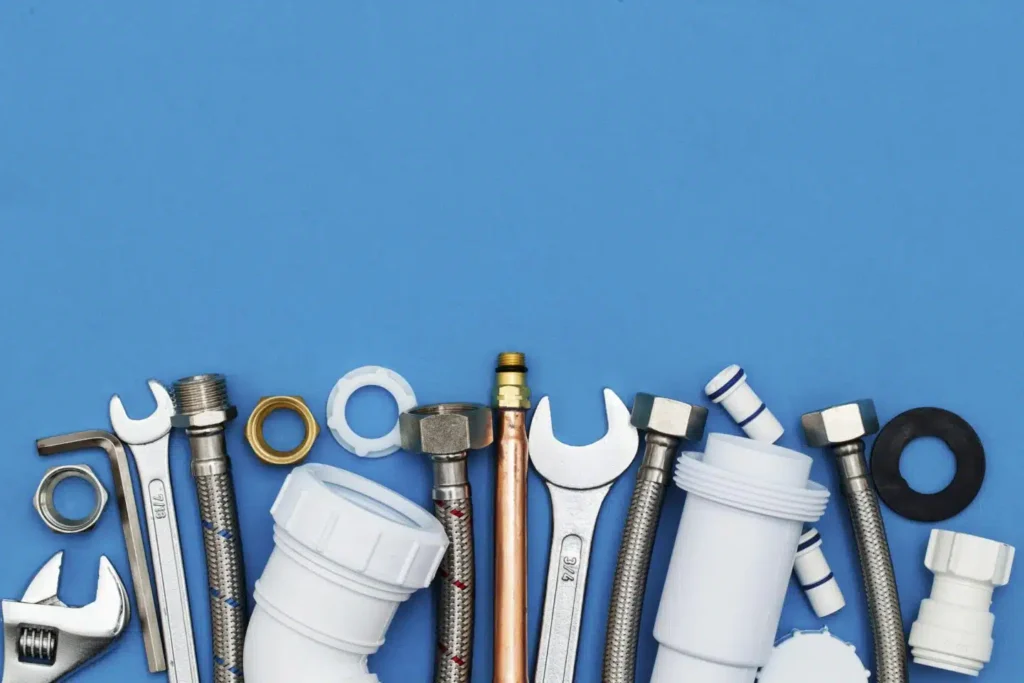 Wrenches, pipe fittings and washers lined up on a blue background