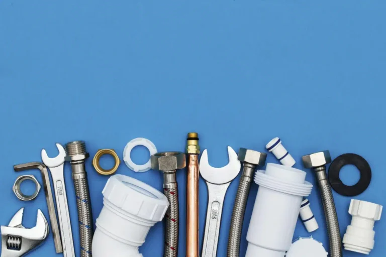 Wrenches, pipe fittings and washers lined up on a blue background