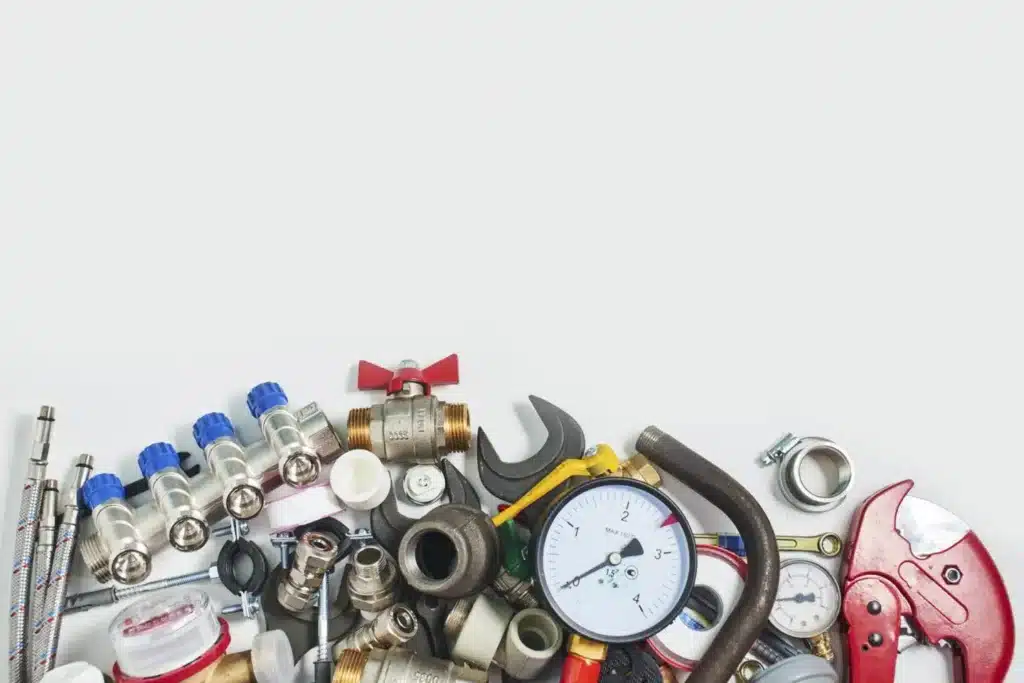 Assorted plumbing fittings, valves and a pressure gauge arranged on a table