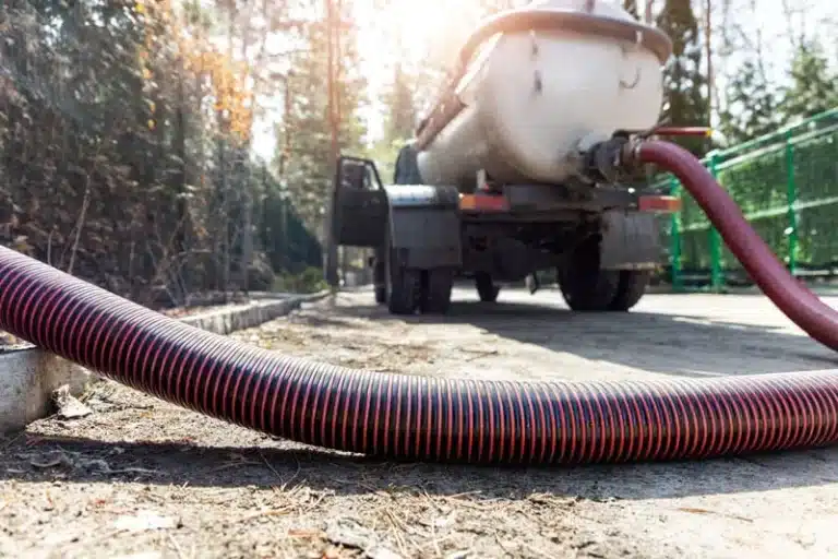 Septic pump truck with a suction hose laid across a driveway